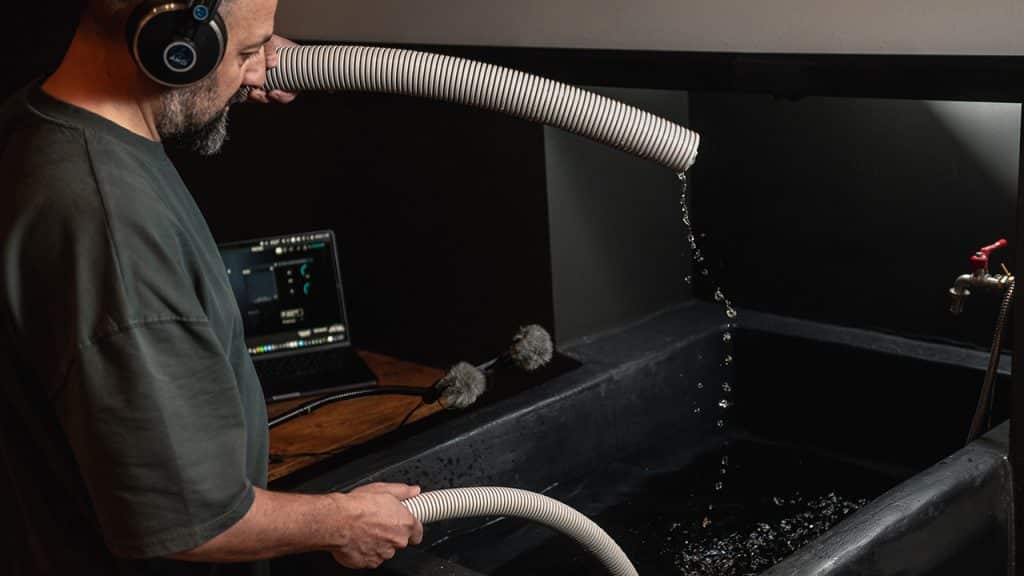 John Valasis in his studio recording water dripping from tubes into a tub.